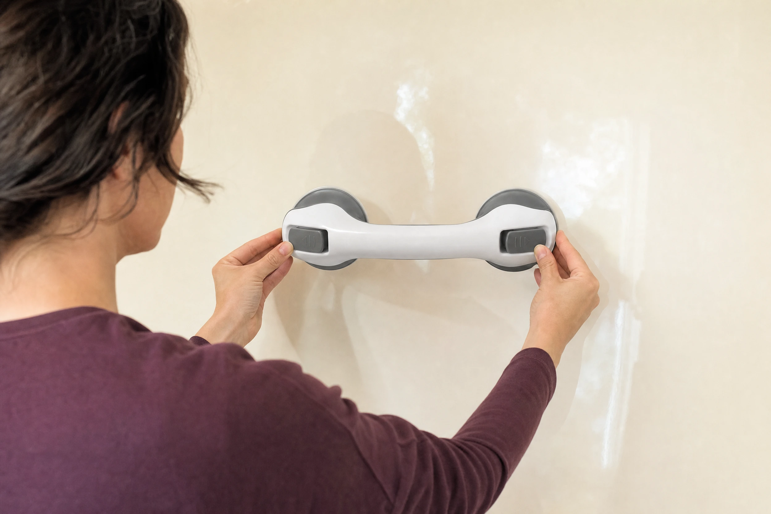 An adult holds a suction handle in front of a tile.